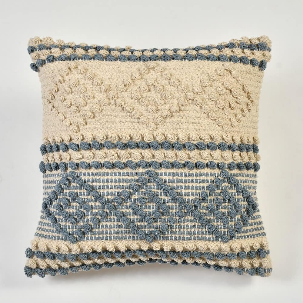 Decorative pillow with textured pattern and pom-pom details on a white background