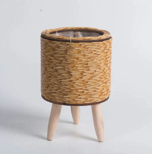 Wicker plant pot with wooden legs on a light gray background