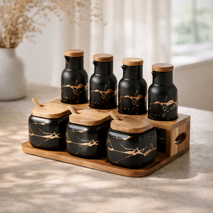 Set of black ceramic jars with wooden lids on a wooden tray in a kitchen setting.