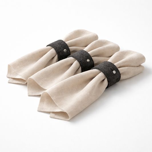 Set of beige napkins with black napkin rings on a white background