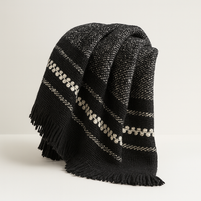 Black plaid blanket with decorative border and fringe on a light background