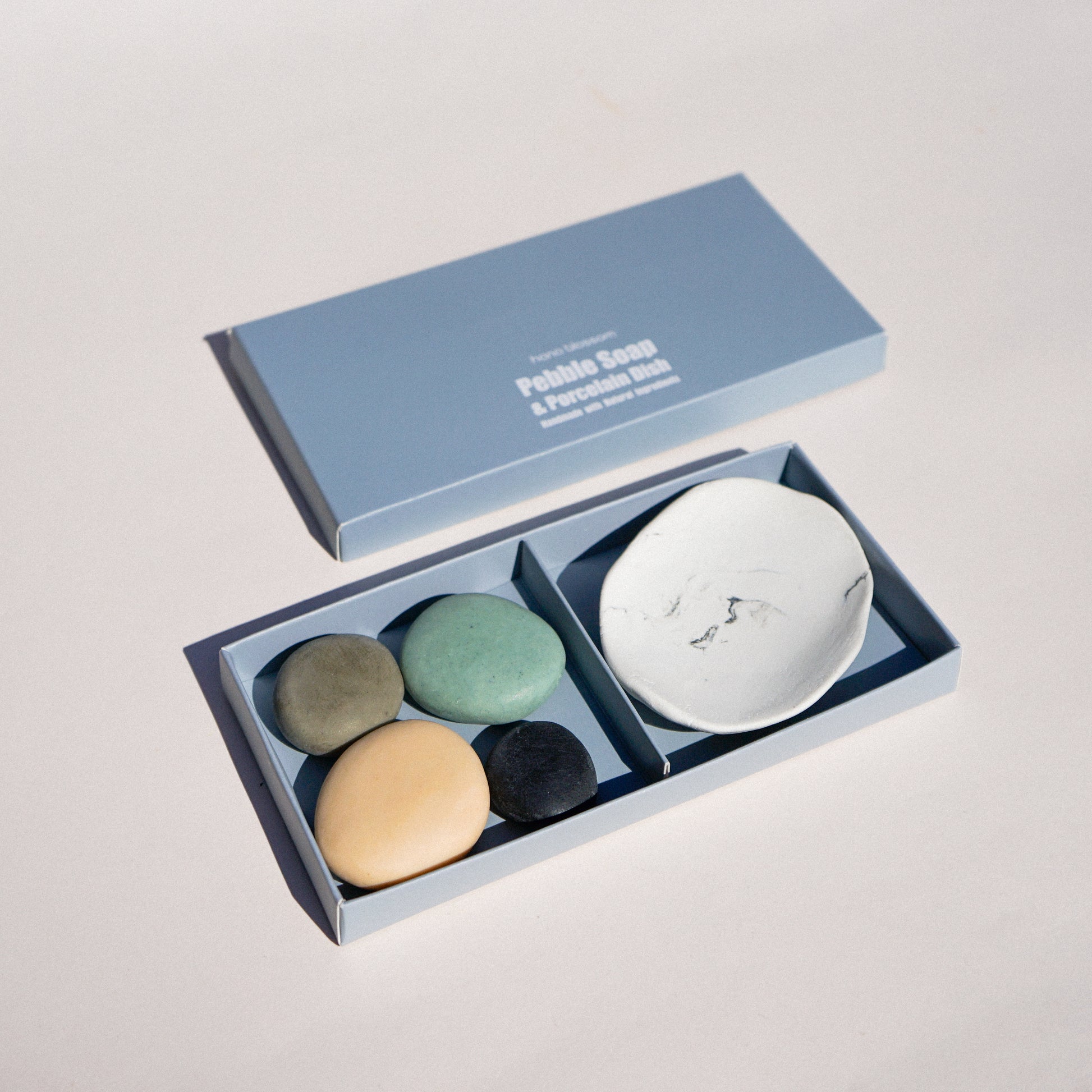 Set of stones and a small dish in an open box on a light gray background