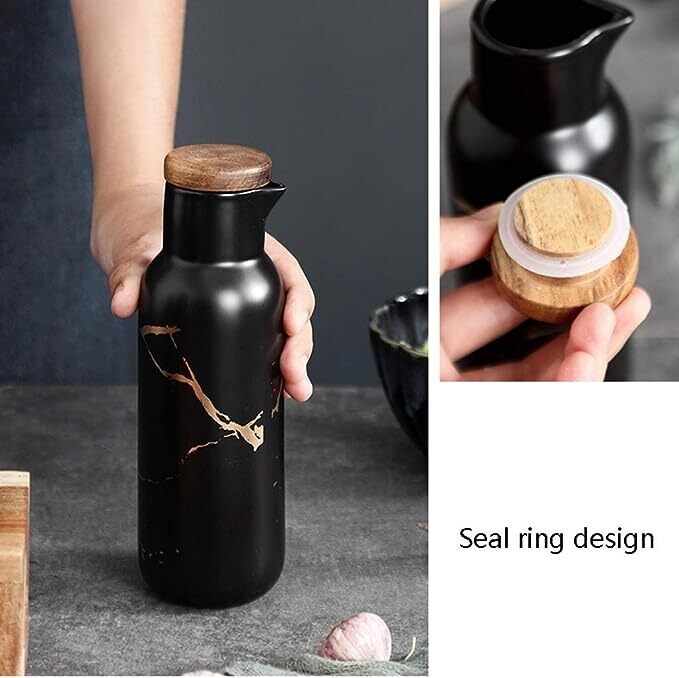 Black ceramic pitcher with wooden lid held by a hand, close-up of seal ring design.