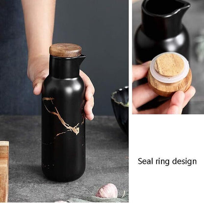 Black ceramic pitcher with wooden lid held by a hand, close-up of seal ring design.