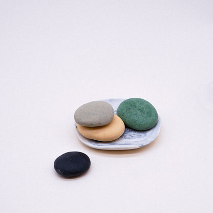 Four colorful stones on a white plate against a light background