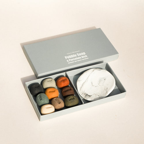 Set of petal-shaped soaps and a marble-textured dish in an open box on a beige background.