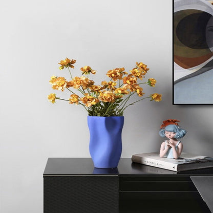 Blue vase with yellow flowers on a black surface next to a framed picture