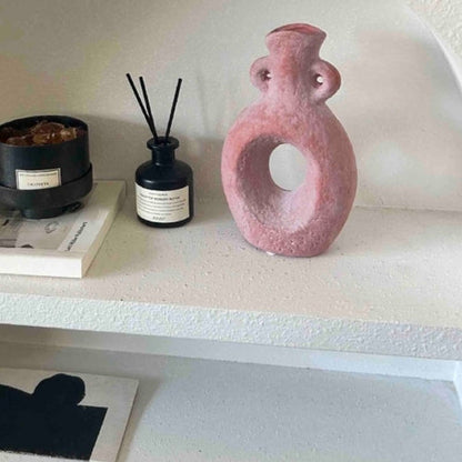 Pink abstract vase on a shelf with decorative items